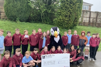 A group of a school children holding a giant cheque with our puffin mascot. 