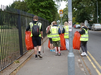 A group of students and staff picking litter along the road. 