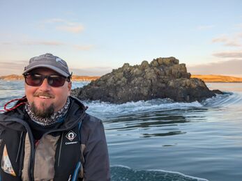 Outreach and Engagement Officer next to the sea with a blue sky