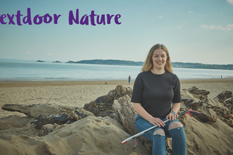 Nextdoor nature a girl sitting on the beach with a litter picker