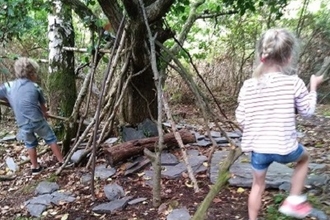 Children using branches to construct a shelter