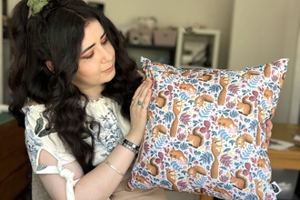 One of our fundraisers, Tahlia, holding a cushion with a squirrel pattern that she designed and made.