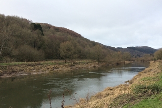 A river in Wales, with a wooded hill on the far bank