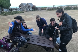 5 weekly volunteers sat in the courtyard on a picnic bench, laughing and looking at moths.