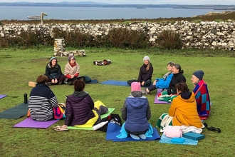 A group of people doing yoga in the courtyard on Skomer.