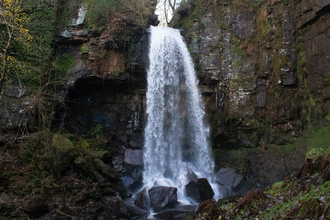 Waterfall falling on big black rocks.
