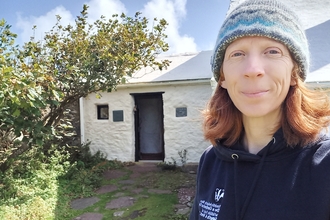 A selfie of Lisa on Skokholm Island. The white cottage is behind her.