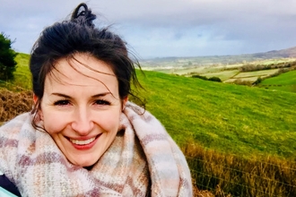A selfie of Beth with green hills behind her. 
