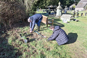 Two people planting bulbs in a churchyard.