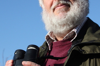 Keith Noble holding a pair of binoculars.