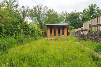 Green meadow in a garden with a pond and shed 