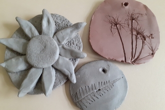3 clay tiles showing leaves and a flower head