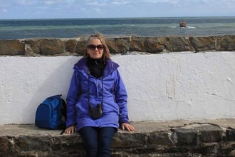 Gretchen sat on a harbour wall with the sea behind her. 
