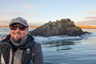 Outreach and Engagement Officer next to the sea with a blue sky