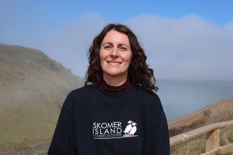 Chloe wearing a Skomer Island jumper at Martin's Haven.