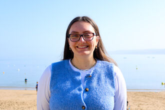 Maddy with the beach and sea behind her. 