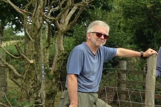 Man leaning against a fence post.
