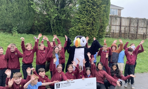 Children holding a giant cheque with our puffin mascot. 