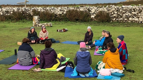 A group of people doing yoga in the courtyard on Skomer.