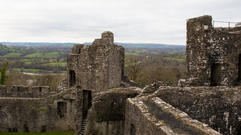 Castle ruins with tree tops and hills in the background.