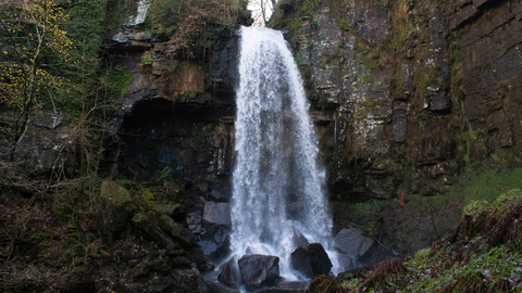 Waterfall falling on big black rocks.