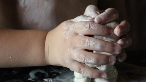 child's hands squeezing clay
