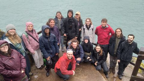 A group of young people on the steps. They are wearing waterproofs and all looking at the camera.