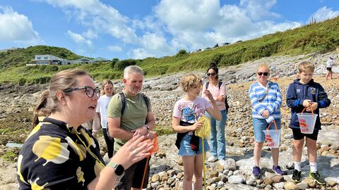 Marine biologist Emma Lowe talking to people on a pebbly beach