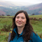 Alice, our Conservation Officer, standing in field with mountains behind her. 