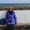Gretchen sat on a harbour wall with the sea behind her. 