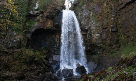 Waterfall falling on big black rocks.