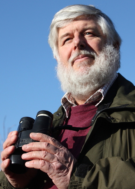 Keith Noble holding a pair of binoculars.