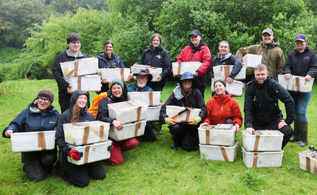 A big group of people holding boxes containing Water Voles.