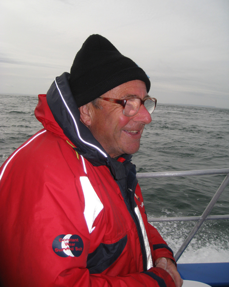 Lyndon in red coat on a boat. 
