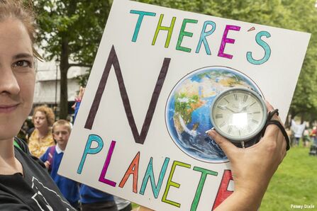 Protestor holding 'There's no Planet B' sign with an alarm clock