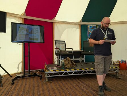 A man stood giving a presentation in a colourful marquee