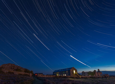 Night sky with stars. Old farm building visible under.