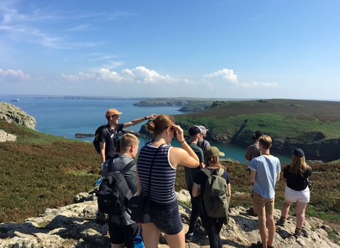 A group standing on a rocky outcrop looking through binoculars