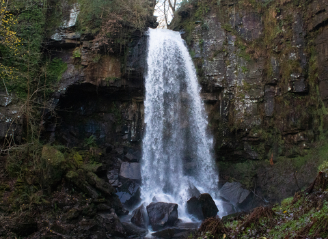 Waterfall falling on big black rocks. 