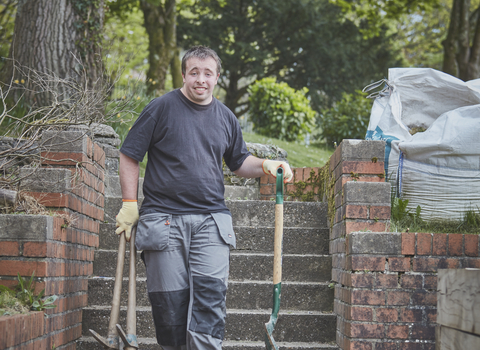 Student carrying gardening equipment on steps